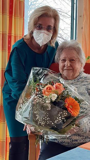 Frau Miniböck sitzt mit Blumenstrauß neben Fr. Dir. Dr. Englmaier.